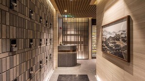 Un couloir avec un mur recouvert de carreaux, un espace de repos central et une œuvre d’art encadrée sur le côté droit.
