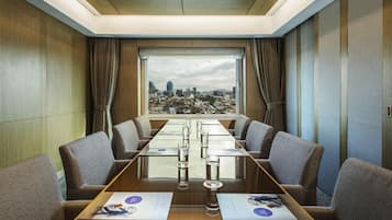 Un salón de conferencias con vistas a la ciudad, una mesa larga y seis sillas.