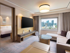 A hotel room with a bed, a TV, a sofa, a coffee table, and a window with a city view. - Novotel Ambassador Seoul Gangnam (Seoul)