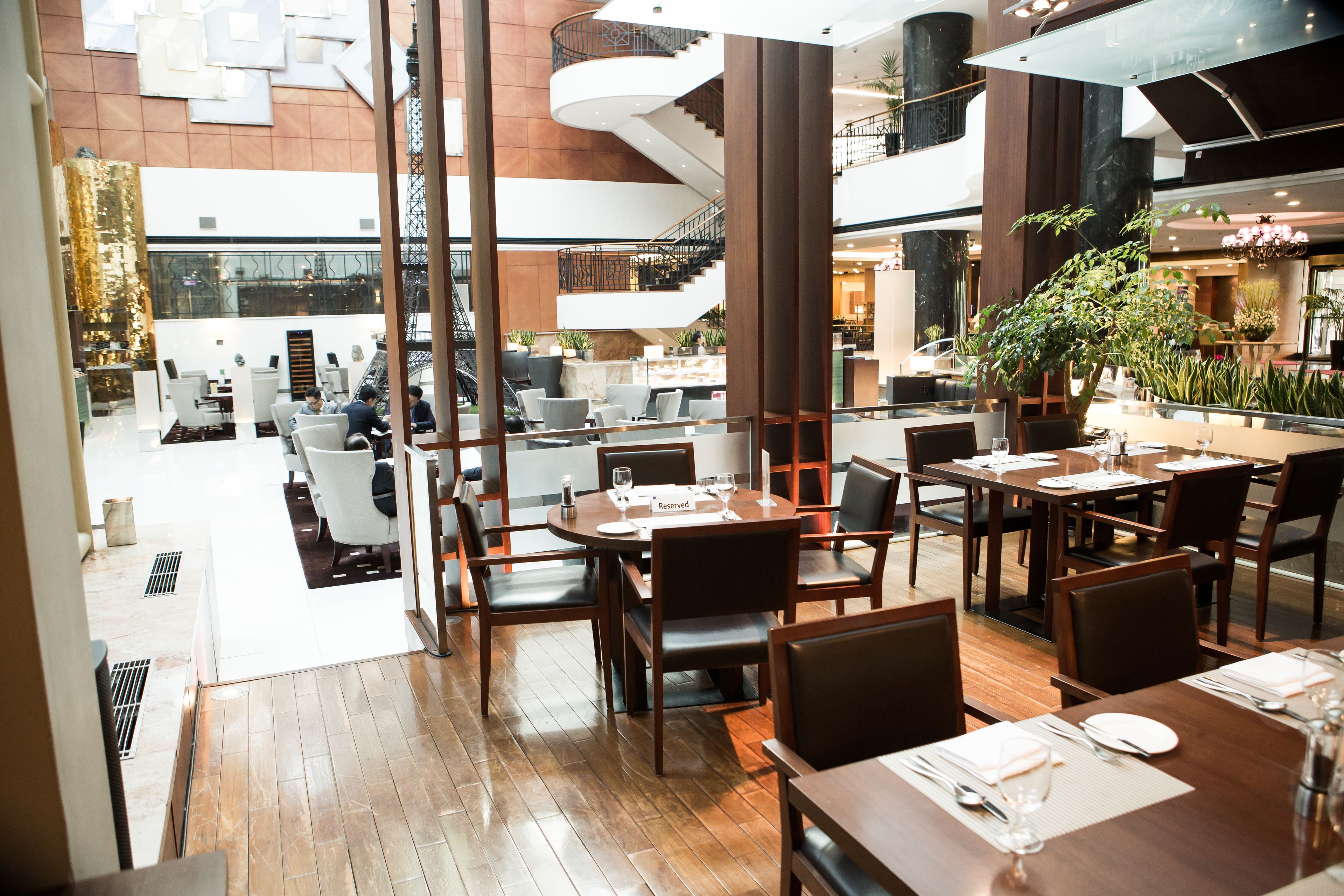 Un moderno vestíbulo de hotel con un amplio espacio de estar, una escalera y una zona de comedor.