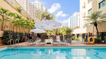 Una piscina al aire libre, sillones reclinables de piscina