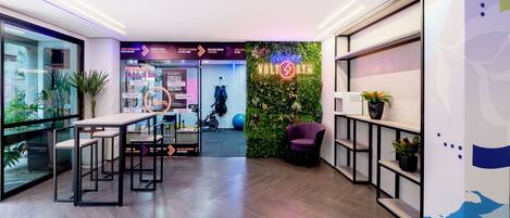 Un espace de bureau moderne comprenant un espace d’accueil, un mur végétal et un coin salon avec un fauteuil violet.