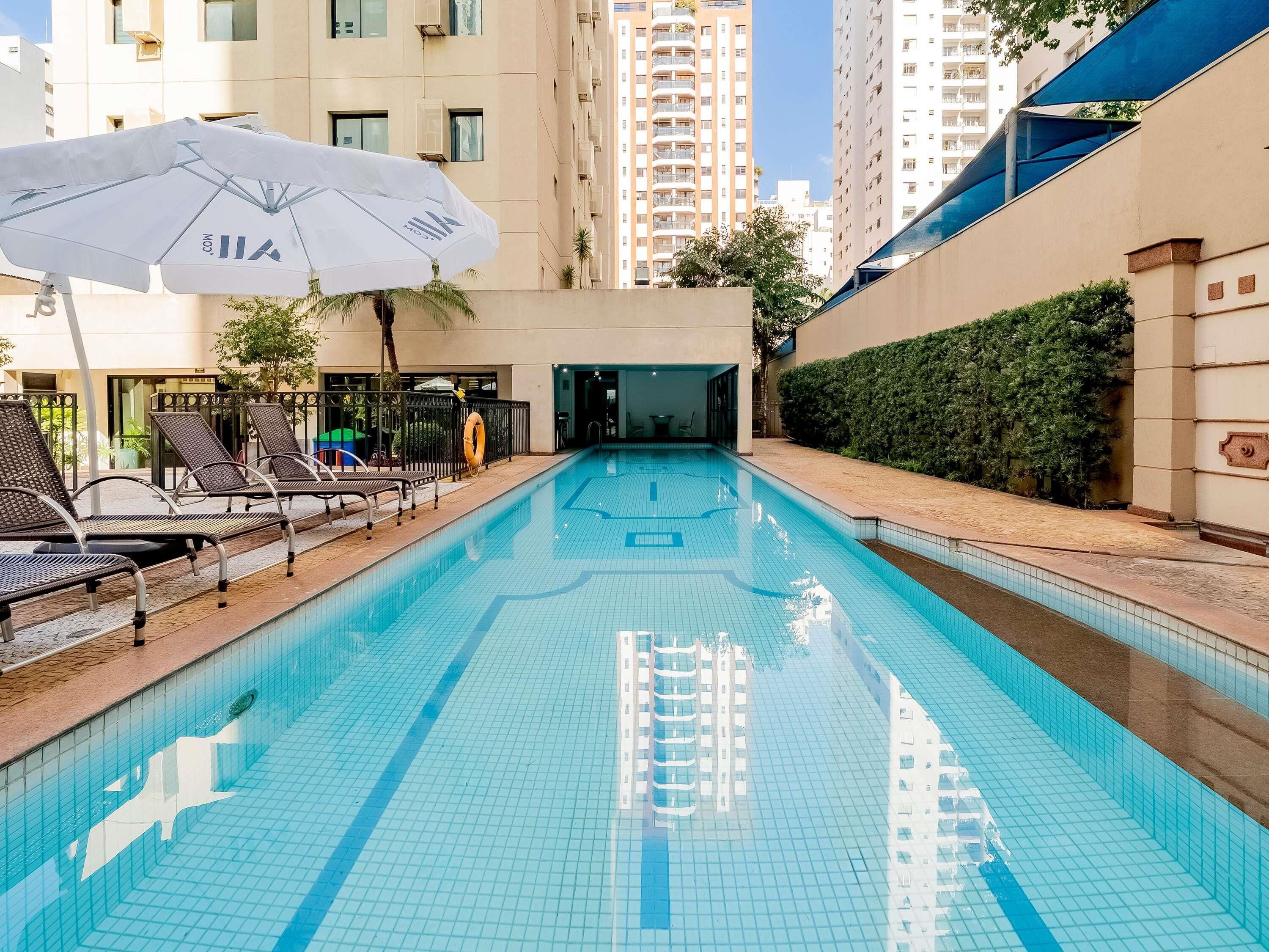 Una piscina al aire libre, sillones reclinables de piscina