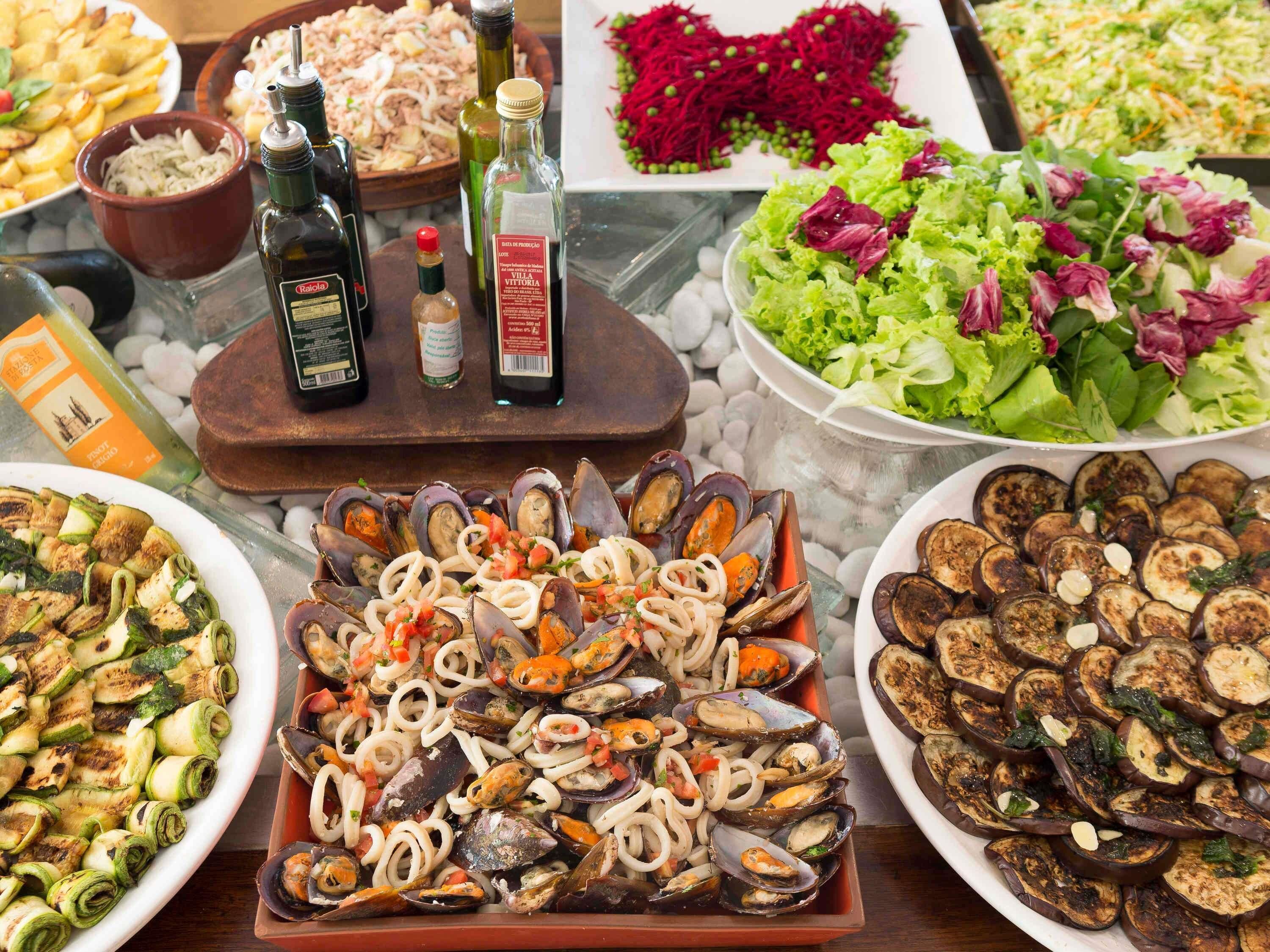 Una variedad de platos de mariscos, incluyendo mejillones y verduras a la parrilla, presentados sobre una mesa.