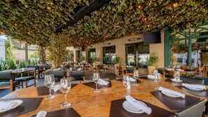 Un espace de restauration intérieur avec des tables dressées, entouré de verdure et baigné de lumière naturelle.