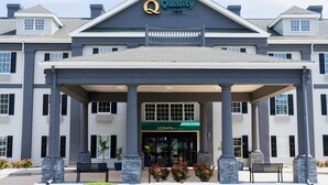 A hotel entrance with a covered porch, columns, and a sign reading "Quality Inn."