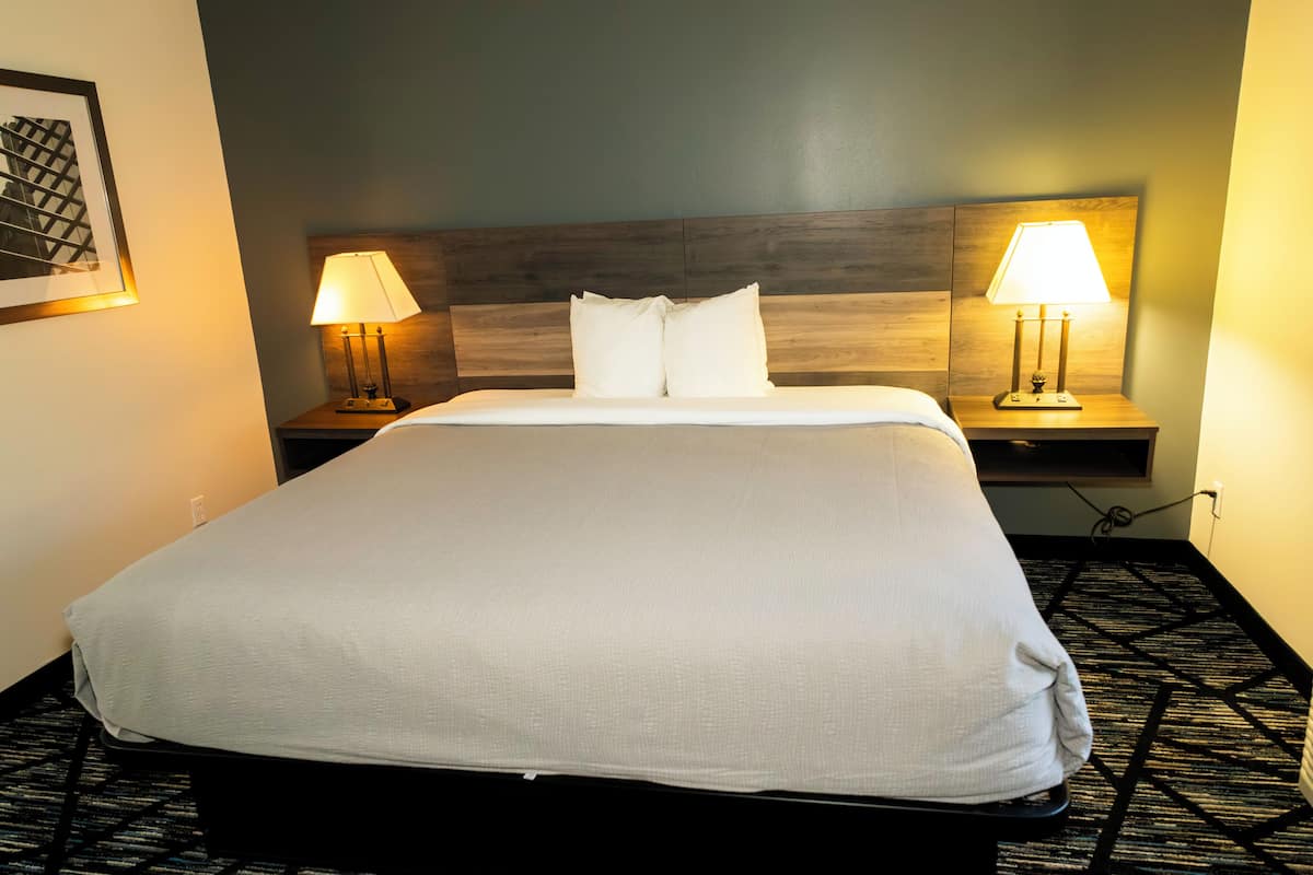 A neatly made bed with white linens, two bedside tables with lamps, and a framed picture on the wall.