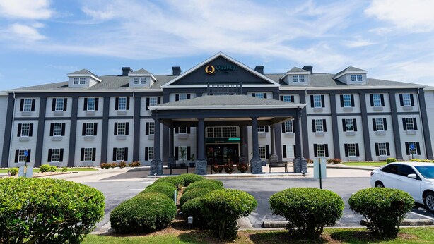 A large hotel with a prominent "Quality" sign, multiple floors, and a covered entrance area.