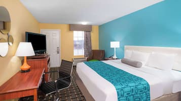A hotel room with a bed, desk, chair, TV, and two lamps.