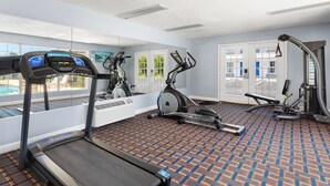 A gym with a treadmill, stationary bikes, and a rowing machine.