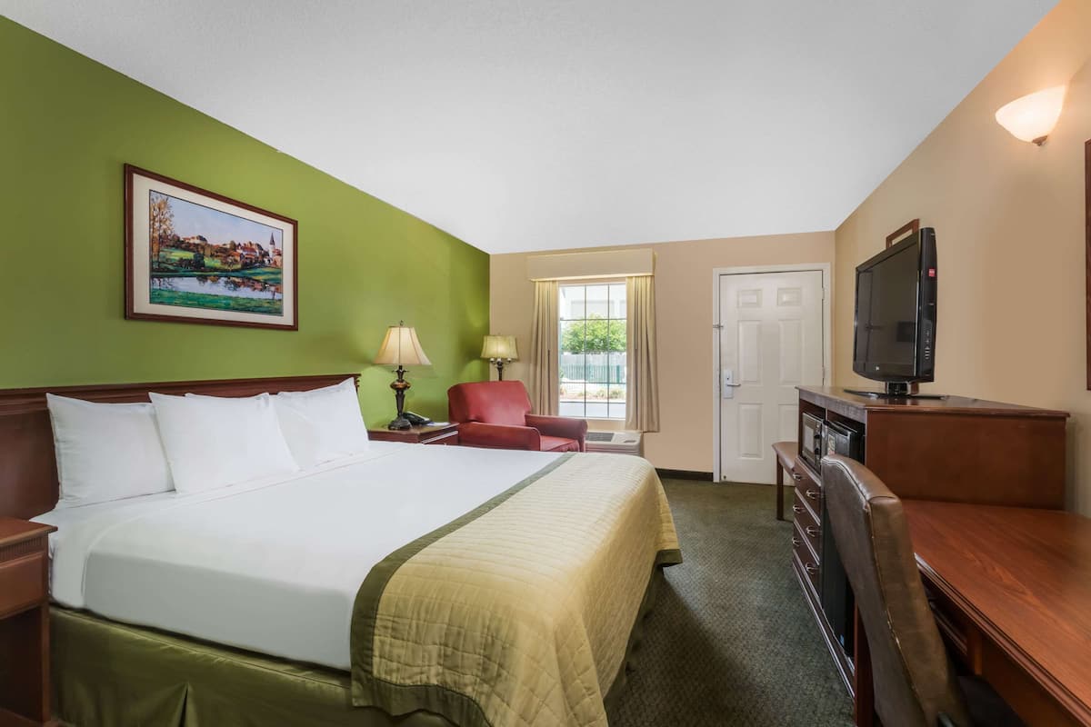 A hotel room with a large bed, a television, a desk, and a chair.