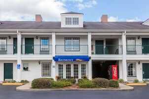 Un motel de dos pisos con un letrero de Baymont, un anuncio de Coca-Cola y un letrero de estacionamiento para discapacitados.