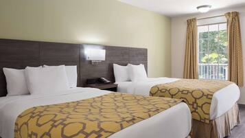 A hotel room with two beds, a bedside table with a phone, a wall-mounted light, and a window with curtains.