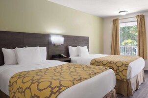 Habitación de hotel con dos camas, una mesita de noche con teléfono, una lámpara de pared y una ventana con cortinas.