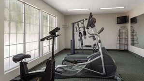 Un gimnasio con cintas de correr, máquinas elípticas y equipo de pesas.