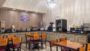 Un área de desayuno con un letrero que dice 'Breakfast Corner', un candelabro, electrodomésticos de cocina y asientos con sillas y mesas de madera.