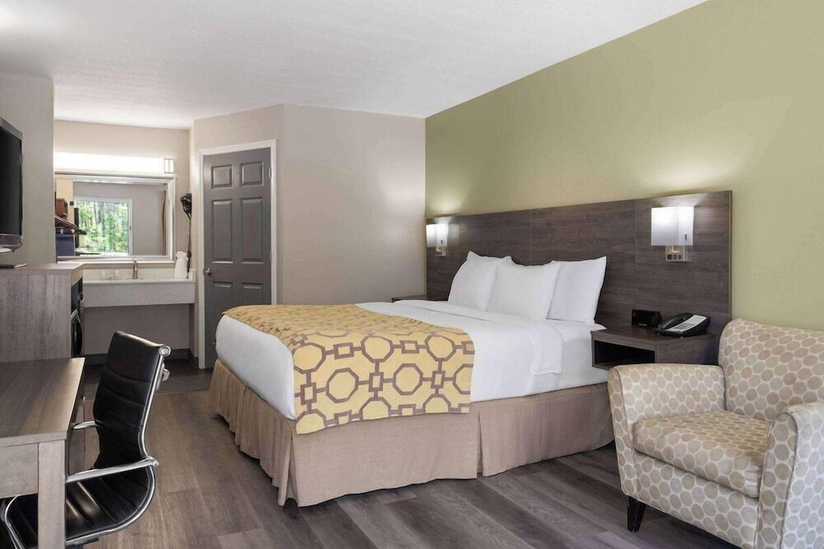 Une chambre d’hôtel avec un lit, un bureau, une chaise, une télévision et une fenêtre.