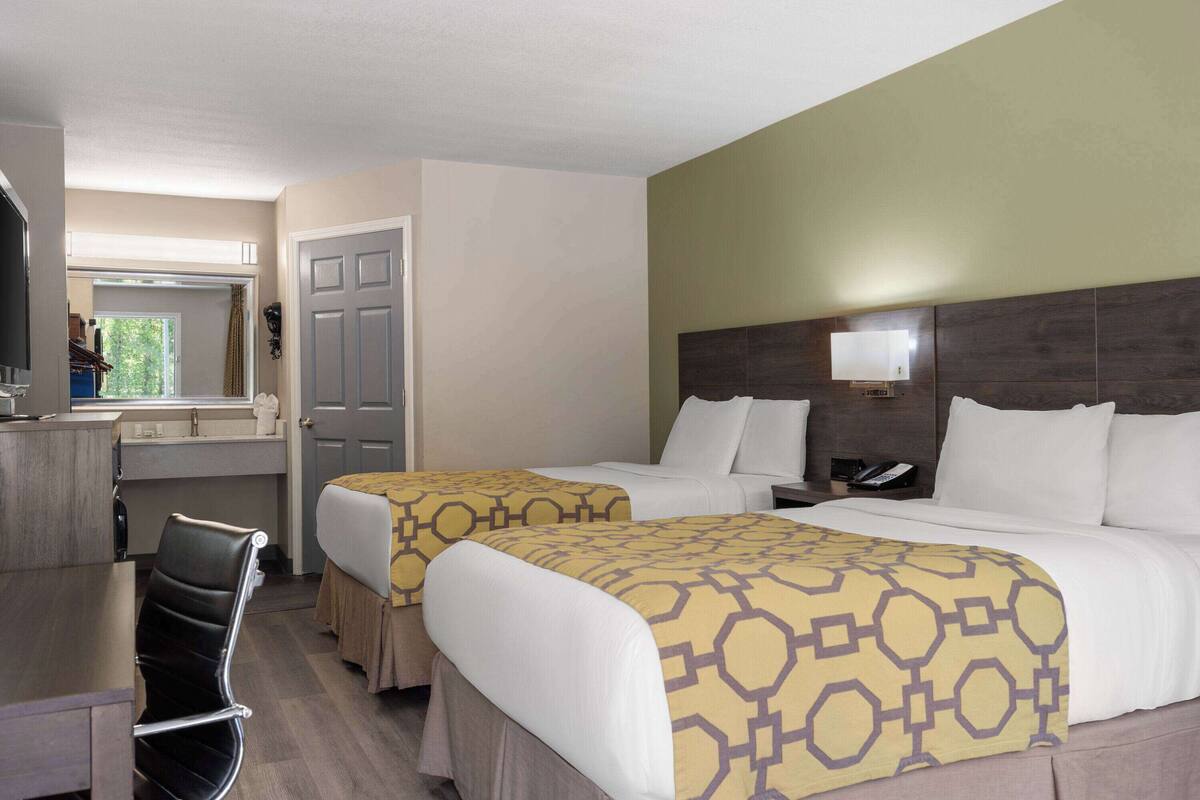 Une chambre d’hôtel avec deux lits, un bureau et une chaise.