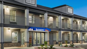 Un hotel de varios pisos con un letrero de "CHECK-IN", balcones y un letrero de "Baymont".