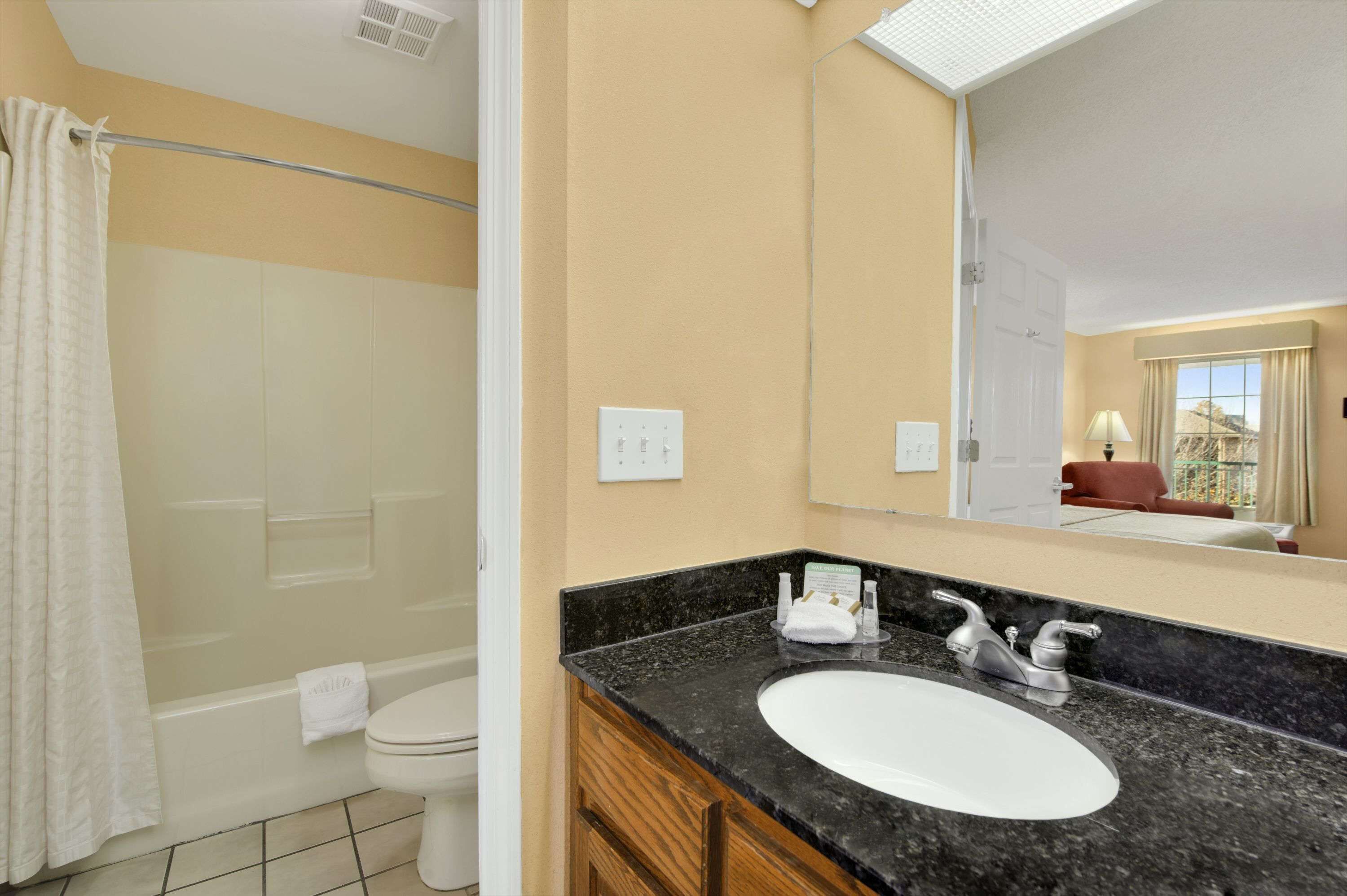 A bathroom with a bathtub, toilet, sink, and mirror.