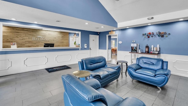 Un área de recepción con el letrero de Baymont, sofás de cuero azul, una mesita y un elemento decorativo en la pared.