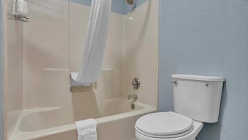 Un baño con bañera, inodoro y cortina de ducha.