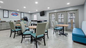 A breakfast area with tables and chairs, a TV mounted on the wall, and a sign that reads "Breakfast Corner." - Baymont by Wyndham Tuscaloosa (Tuscaloosa)
