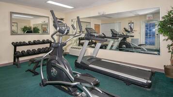 Une salle de sport équipée de tapis de course, d’haltères et d’un banc de musculation.