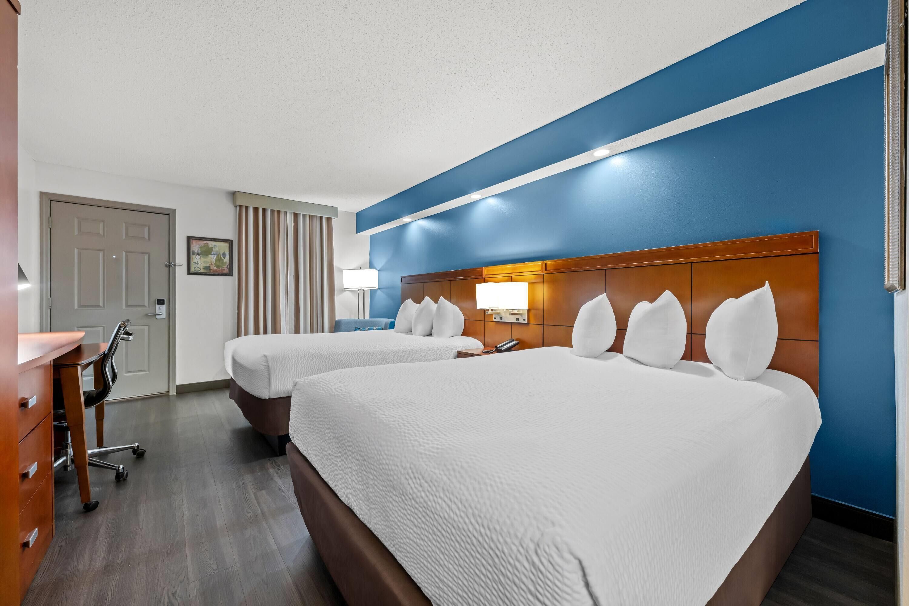 Ein Hotelzimmer mit zwei Betten, einem Schreibtisch und einem Stuhl.
