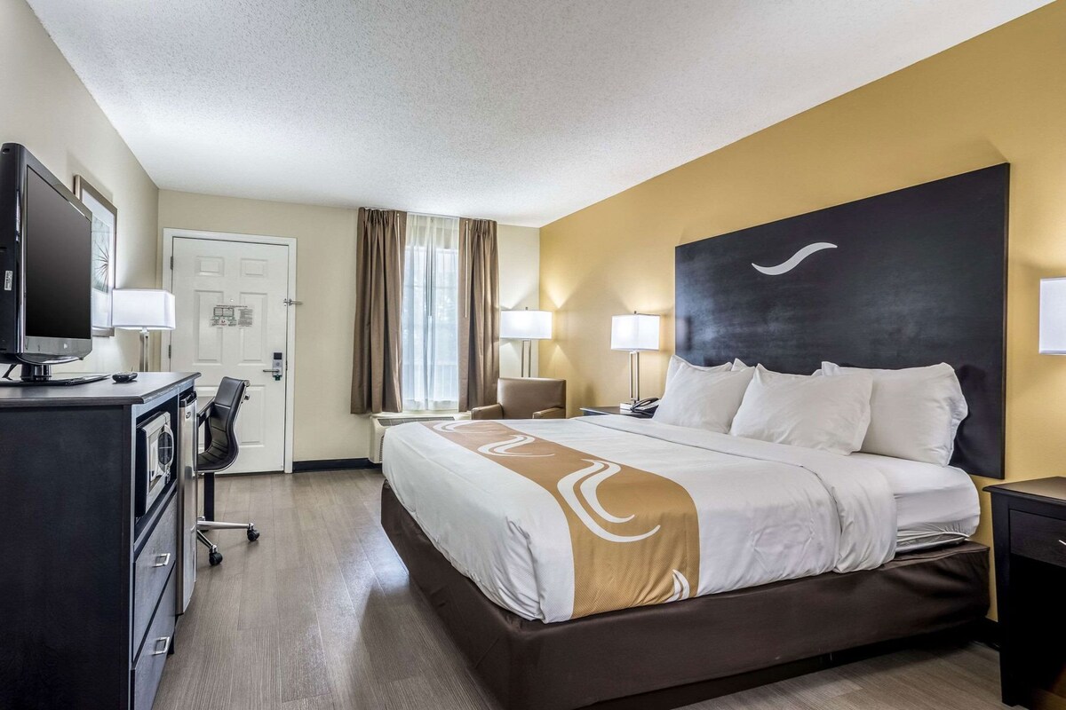 Una habitación de hotel con cama, escritorio, silla y televisión.