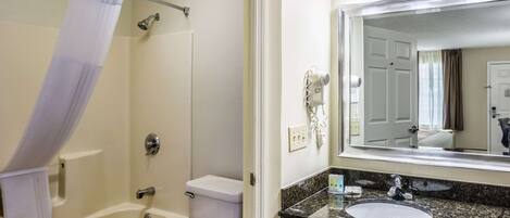 A bathroom with a bathtub, toilet, and a sink with a large mirror above it.