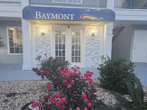 A building with a 'Baymont' sign, a stone facade, and a flower bed with pink flowers. - Baymont by Wyndham Valdosta at Valdosta Mall (Valdosta)
