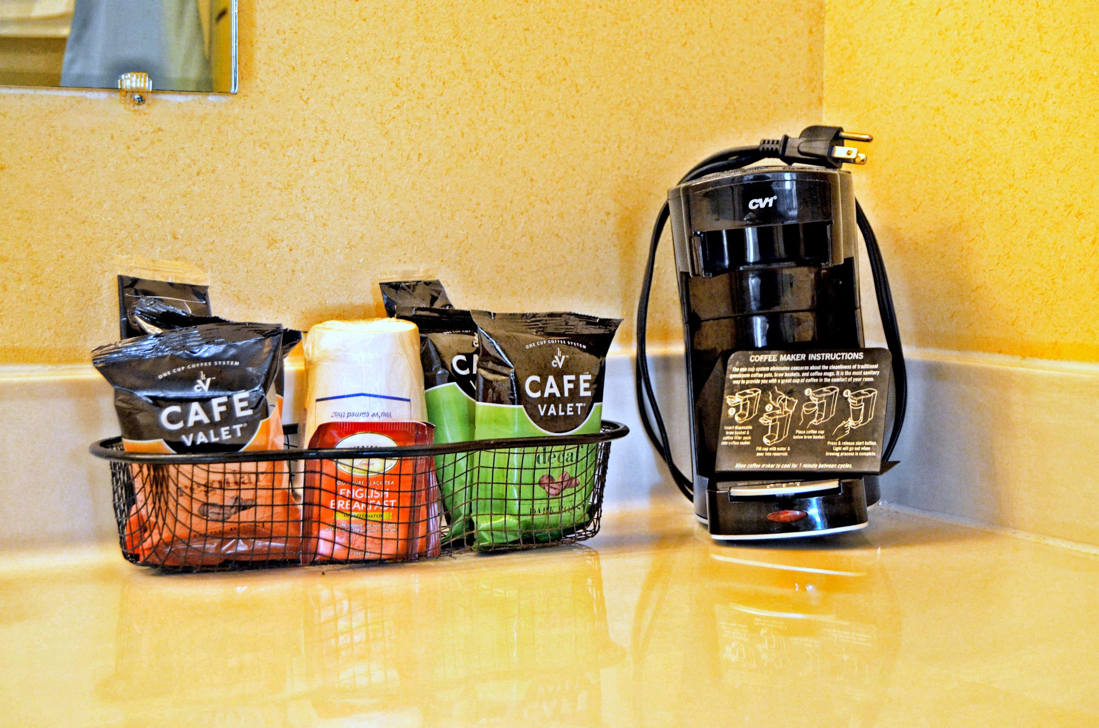 Une machine à café, un panier contenant des dosettes de café et une bouteille de crème sur un plan de travail de cuisine.