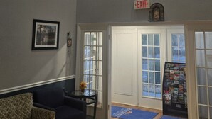 A high-ceiling room with a ceiling fan, a large window, and a door with an exit sign. - Baymont by Wyndham Valdosta at Valdosta Mall (Valdosta)