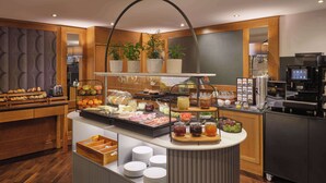 En buffet med forskellige spisemuligheder, en kaffemaskine og en plante.
