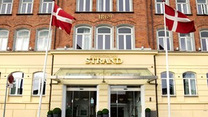 Rakennuksessa on kyltti, jossa lukee ”Copenhagen Strand”, ja sen edessä on kaksi lippua.