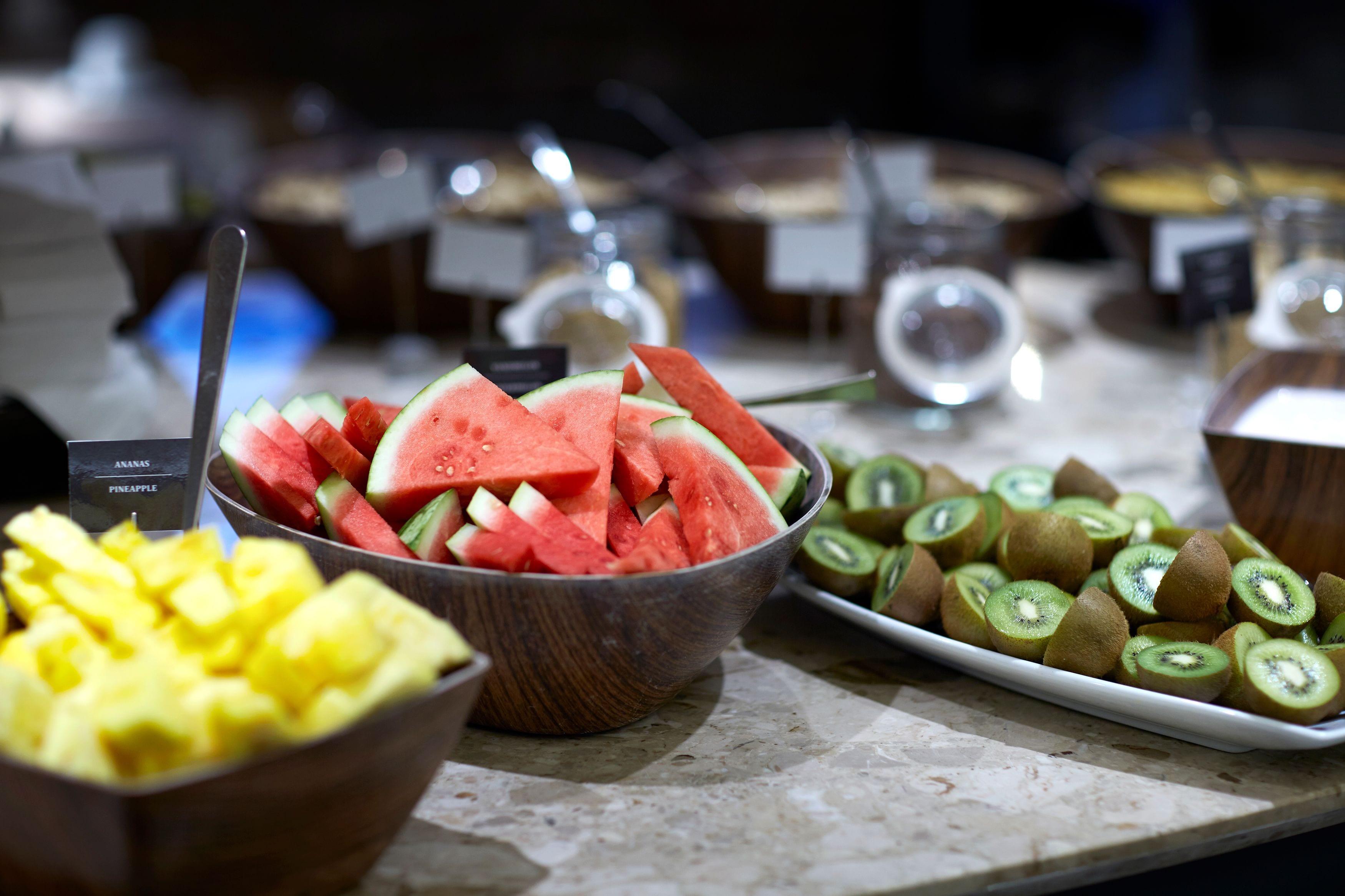 A buffet with various fruits including watermelon, pineapple, and kiwi.
