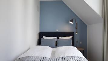 Un dormitorio con cama, cabecera, mesita de noche y lámpara.