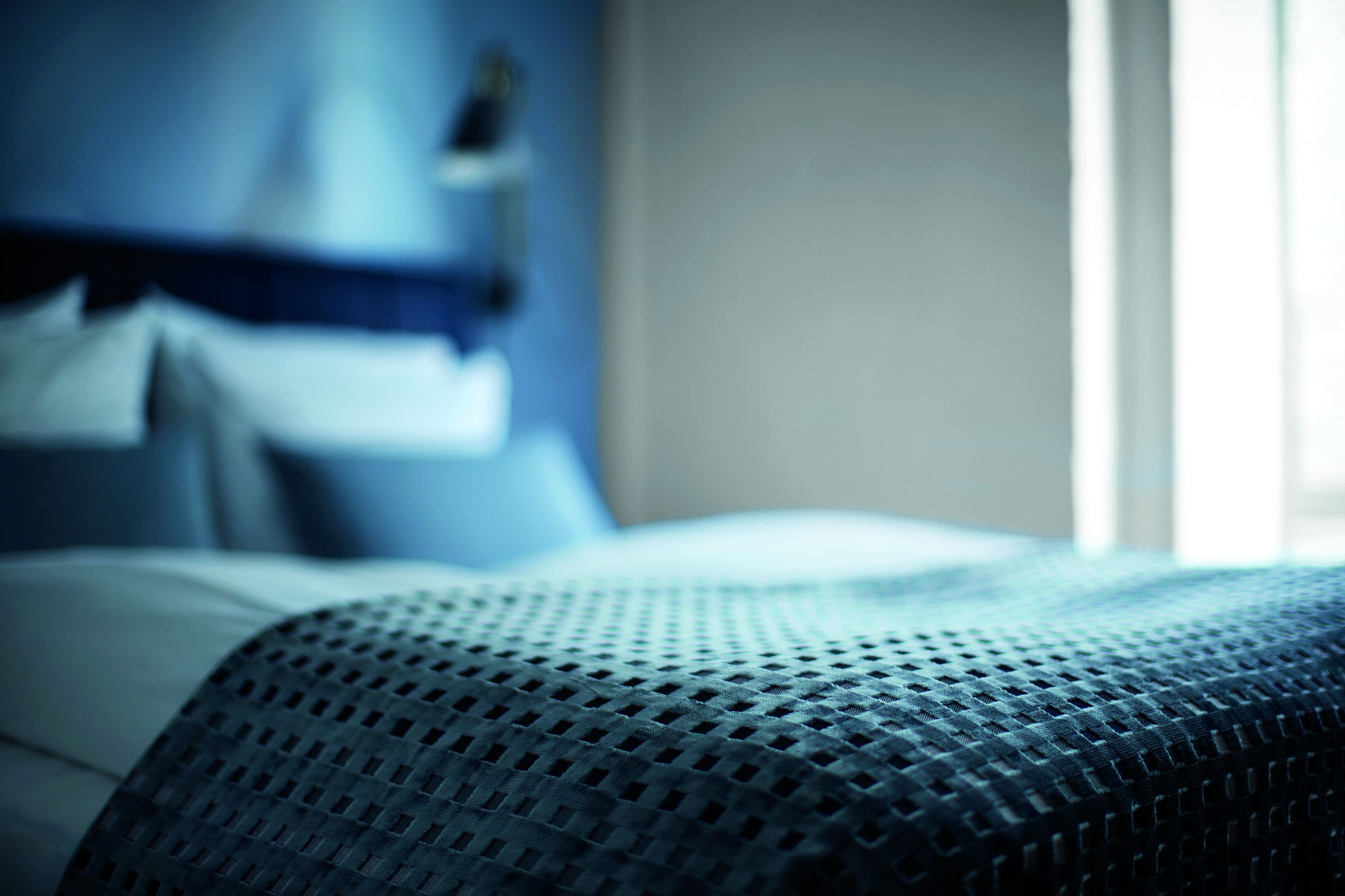Primer plano de una cama con una colcha azul con textura.