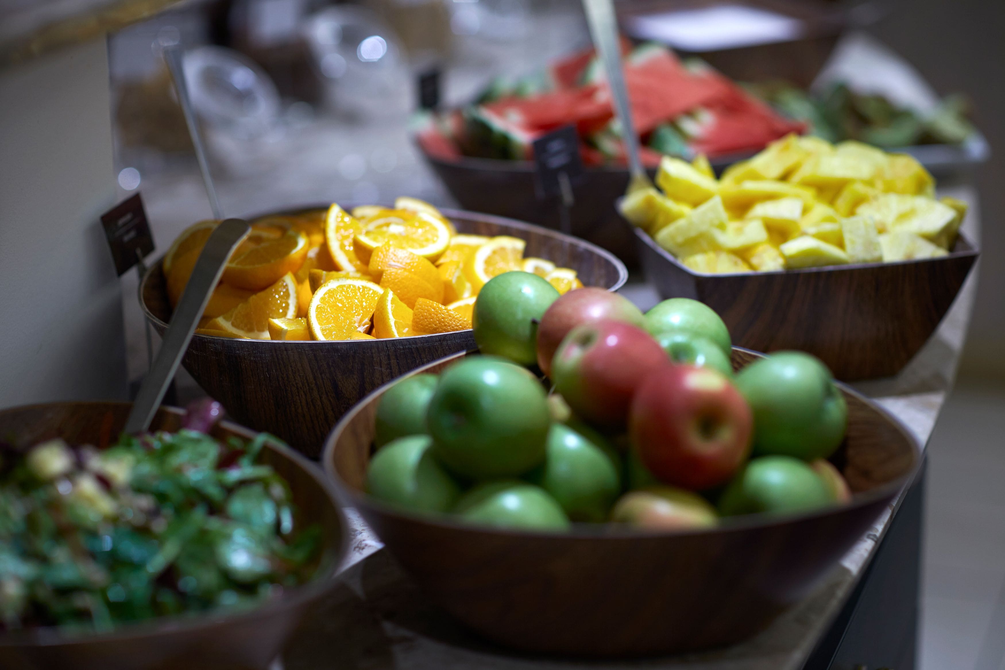 Un bufé con diversas frutas y ensaladas.