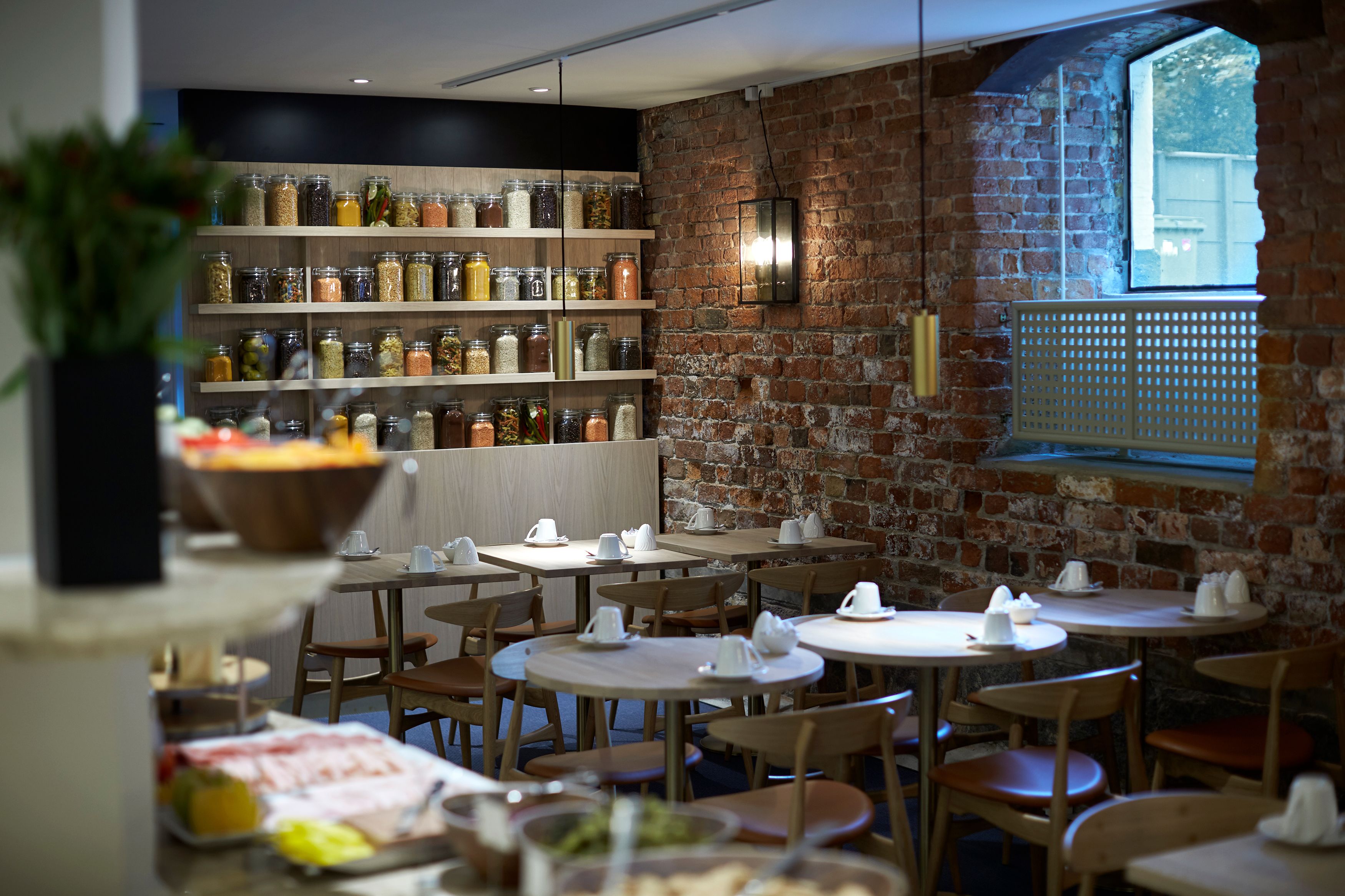 A restaurant with brick walls, wooden tables, and shelves of jars.