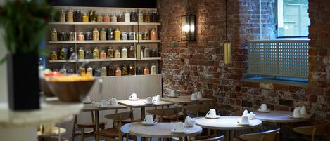 Un restaurante con paredes de ladrillo, mesas de madera y estantes llenos de frascos.