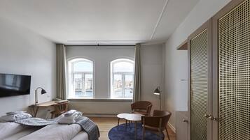 A hotel room with a bed, a desk, a chair, a TV, and a wardrobe.