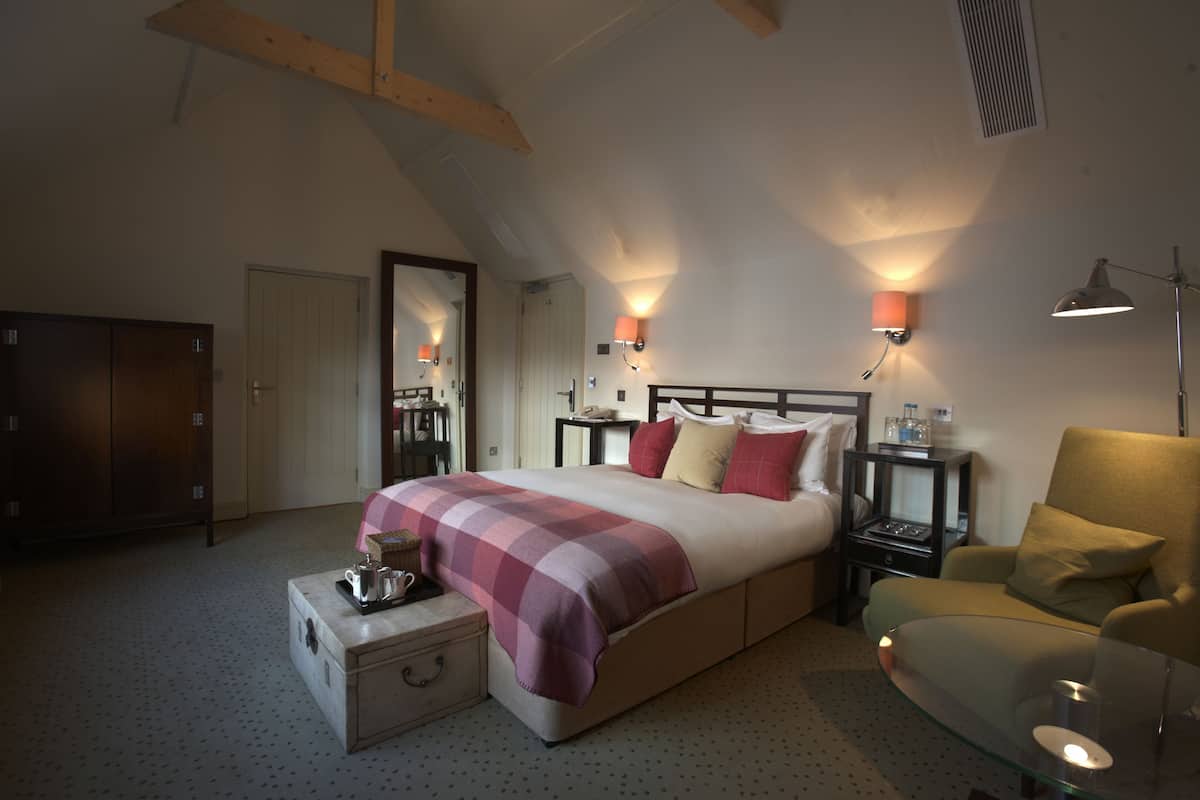 A bedroom with a large bed, a nightstand, a chair, a dresser, and a mirror.