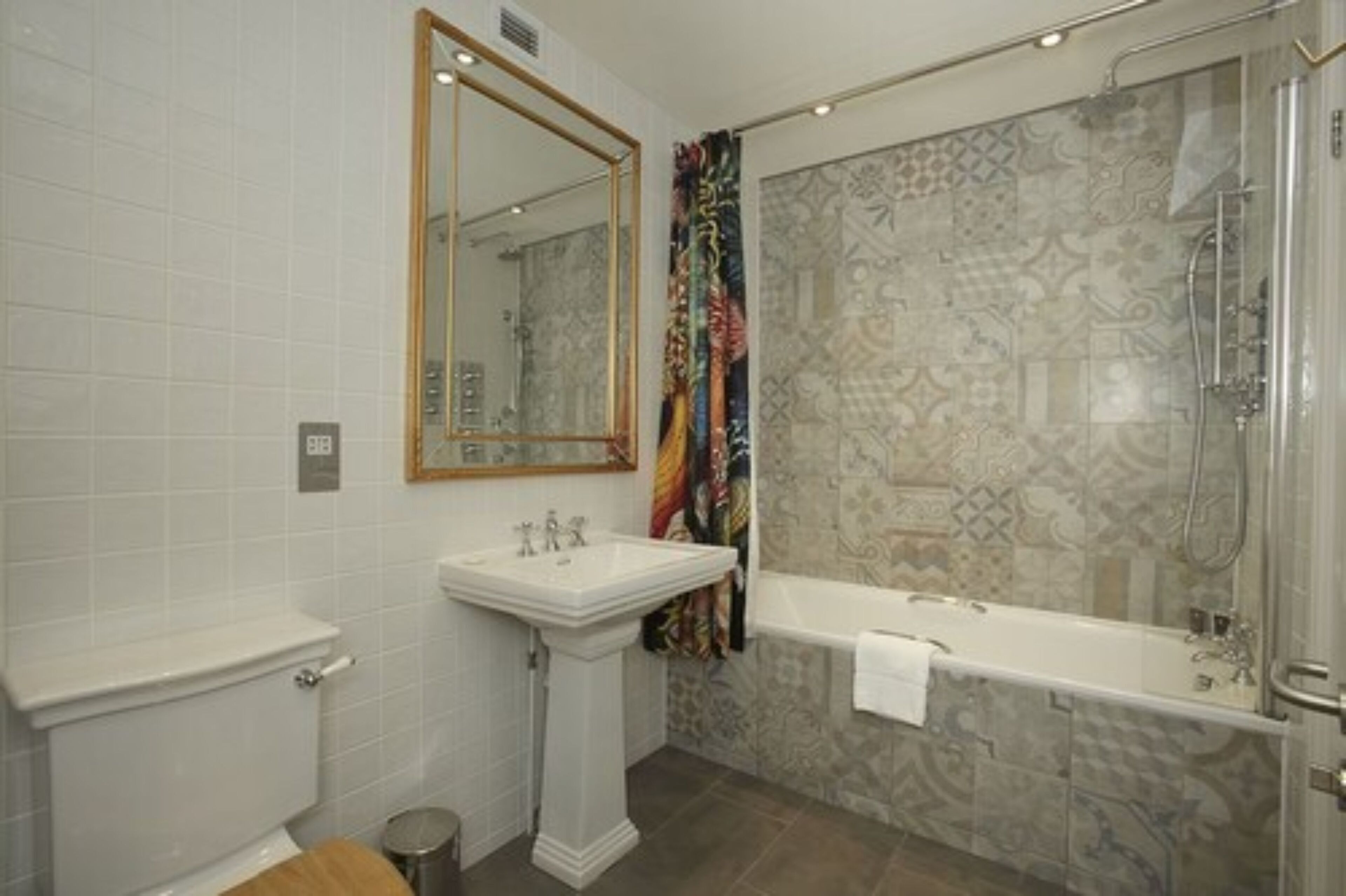 A bathroom with a white toilet, pedestal sink, and a bathtub with a shower.