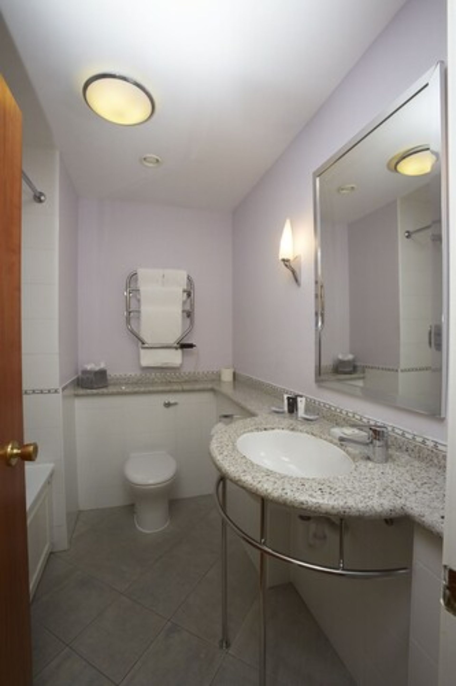 Une petite salle de bain avec un lavabo blanc, des toilettes et un grand miroir.