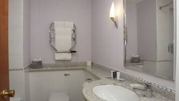 Une petite salle de bain avec un lavabo blanc, des toilettes et un grand miroir.