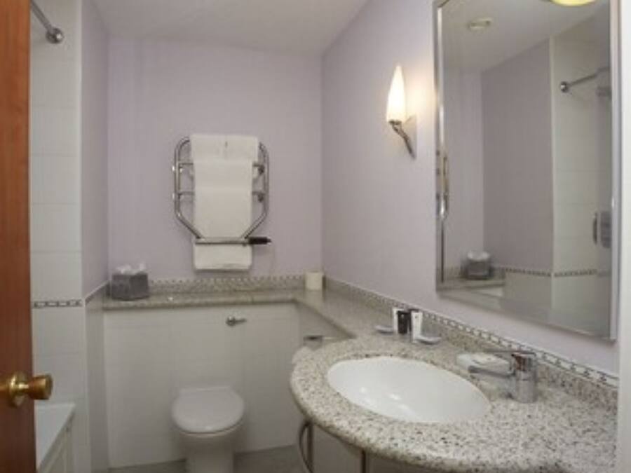 Une petite salle de bain avec un lavabo blanc, des toilettes et un grand miroir.