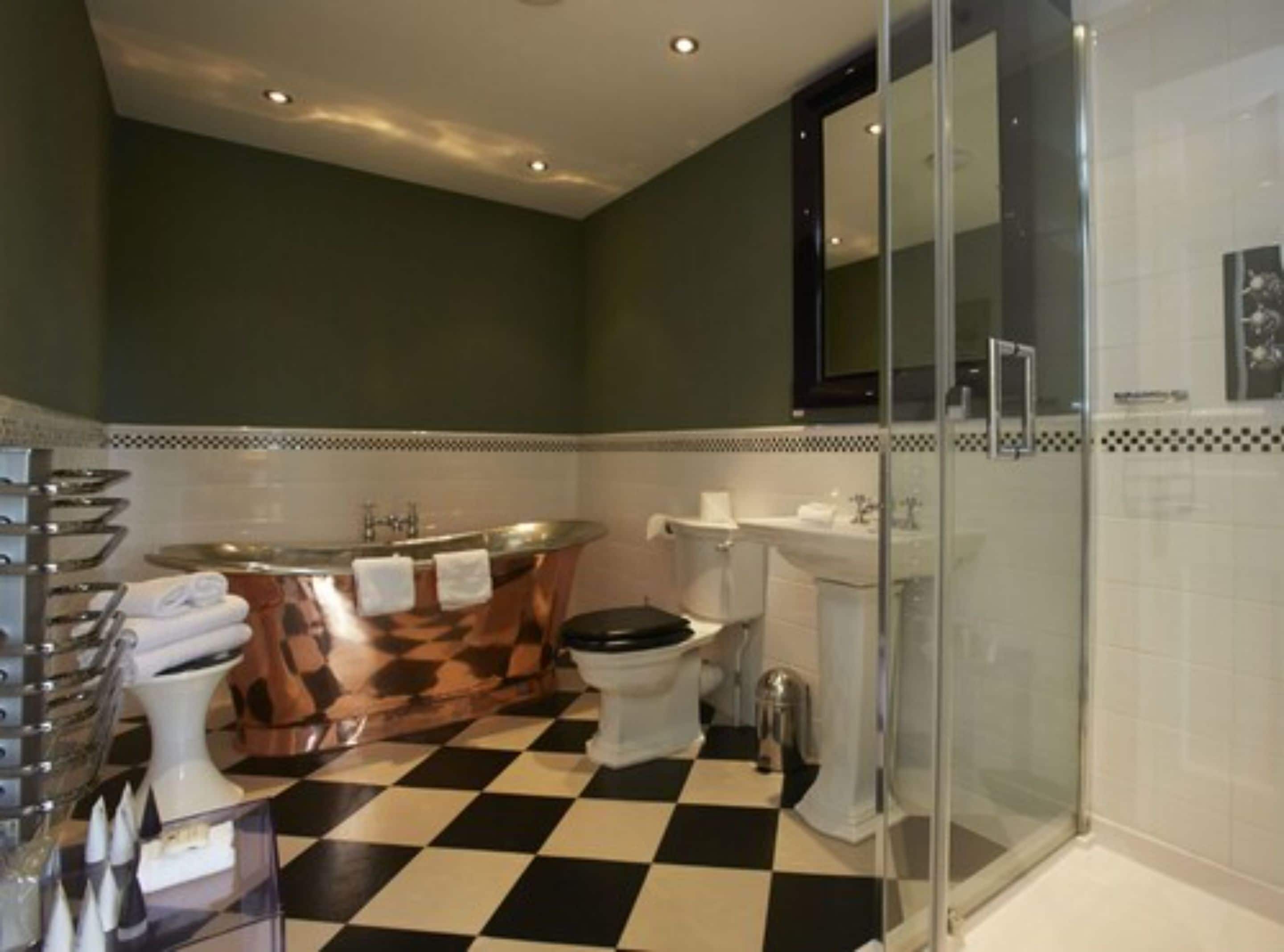 A bathroom with a checkered floor, a bathtub, a toilet, and a glass shower enclosure.