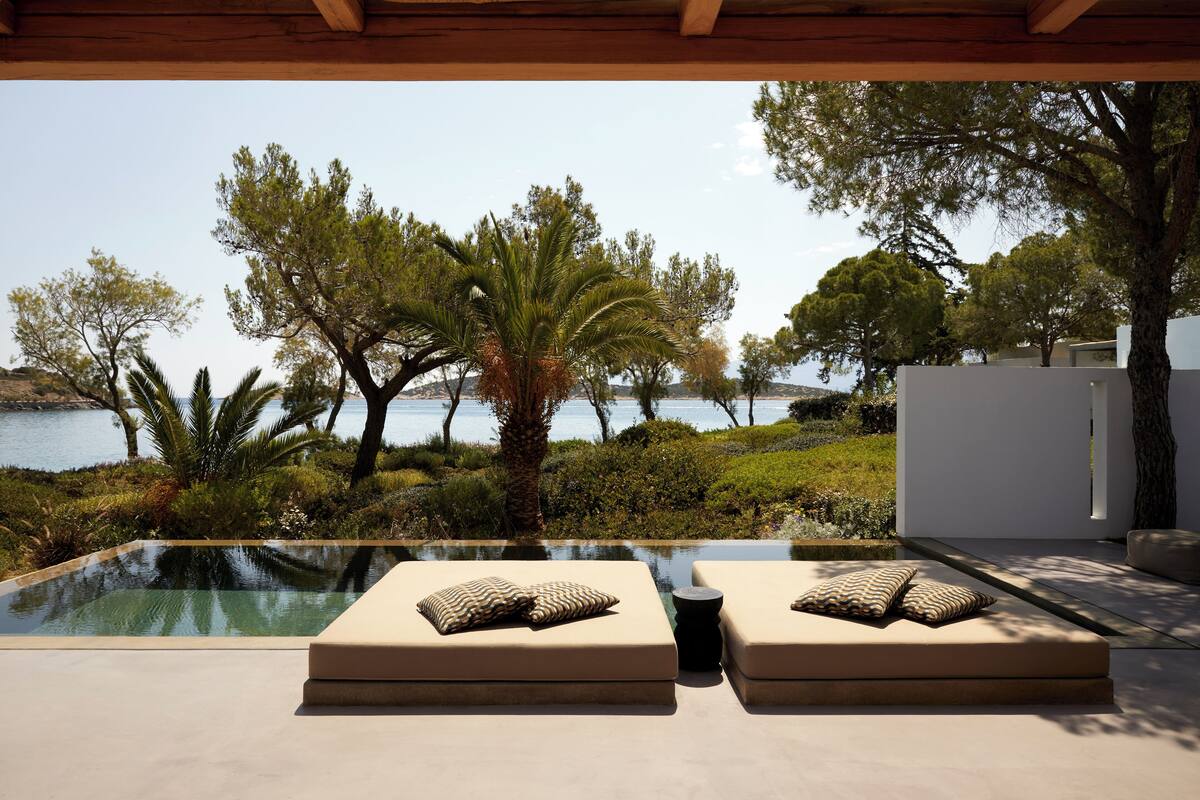 Zona junto a la piscina con dos tumbonas y vistas al mar.